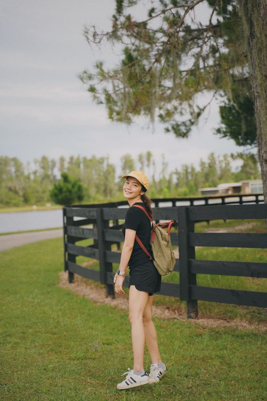 Smiling woman with backpack walking outdoors on a sunny day.