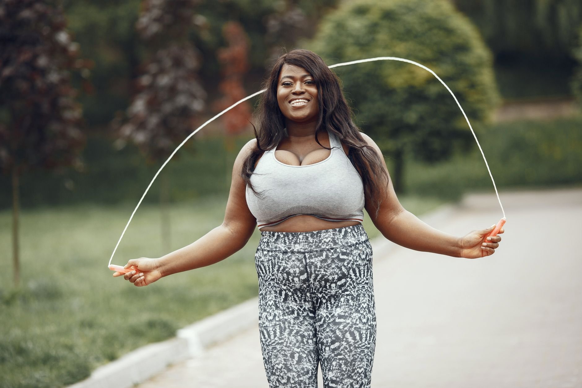 African American woman enjoying a jump rope workout outdoors, smiling.