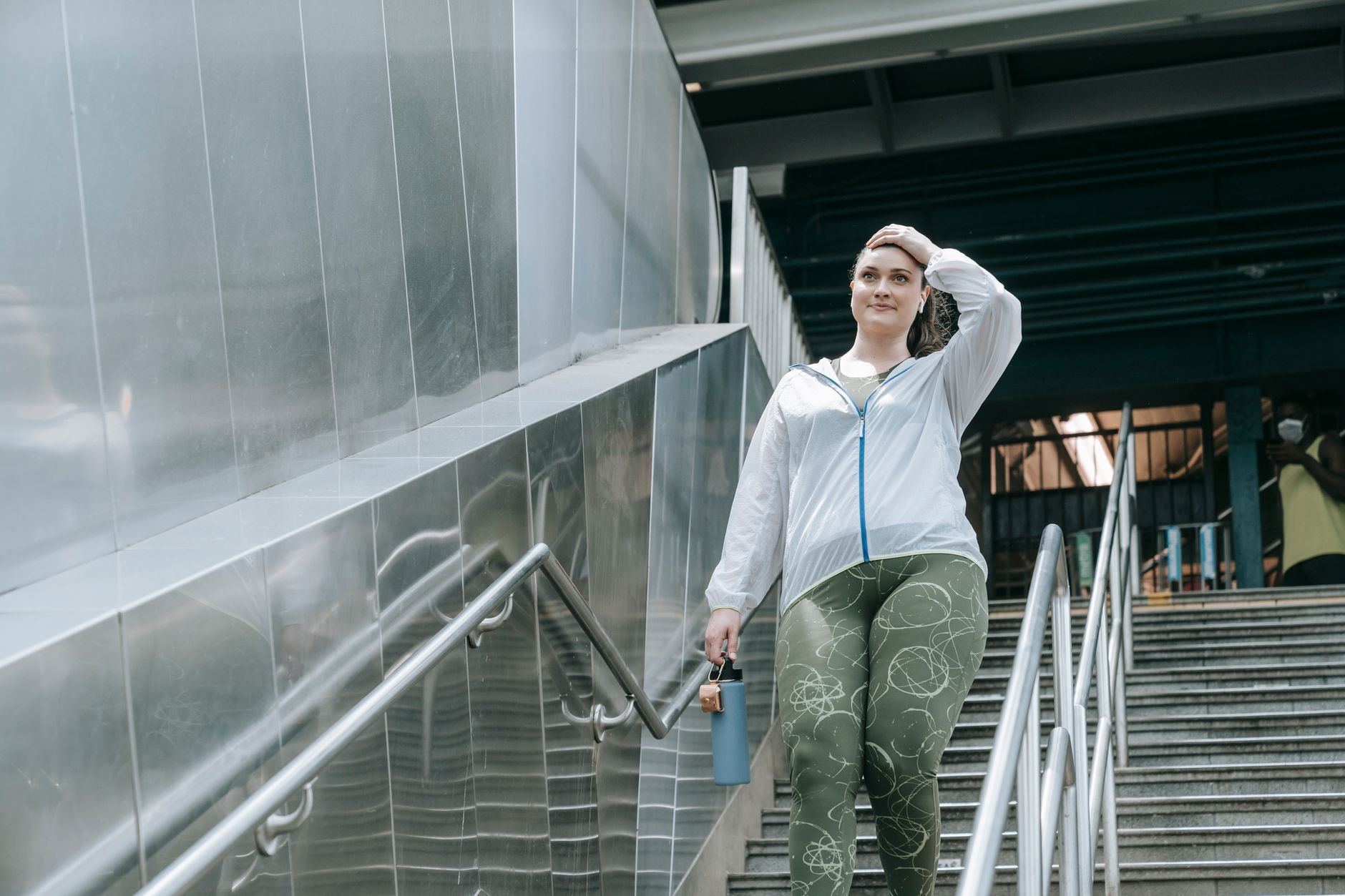 A woman in activewear walks down an outdoor staircase, showcasing urban lifestyle.